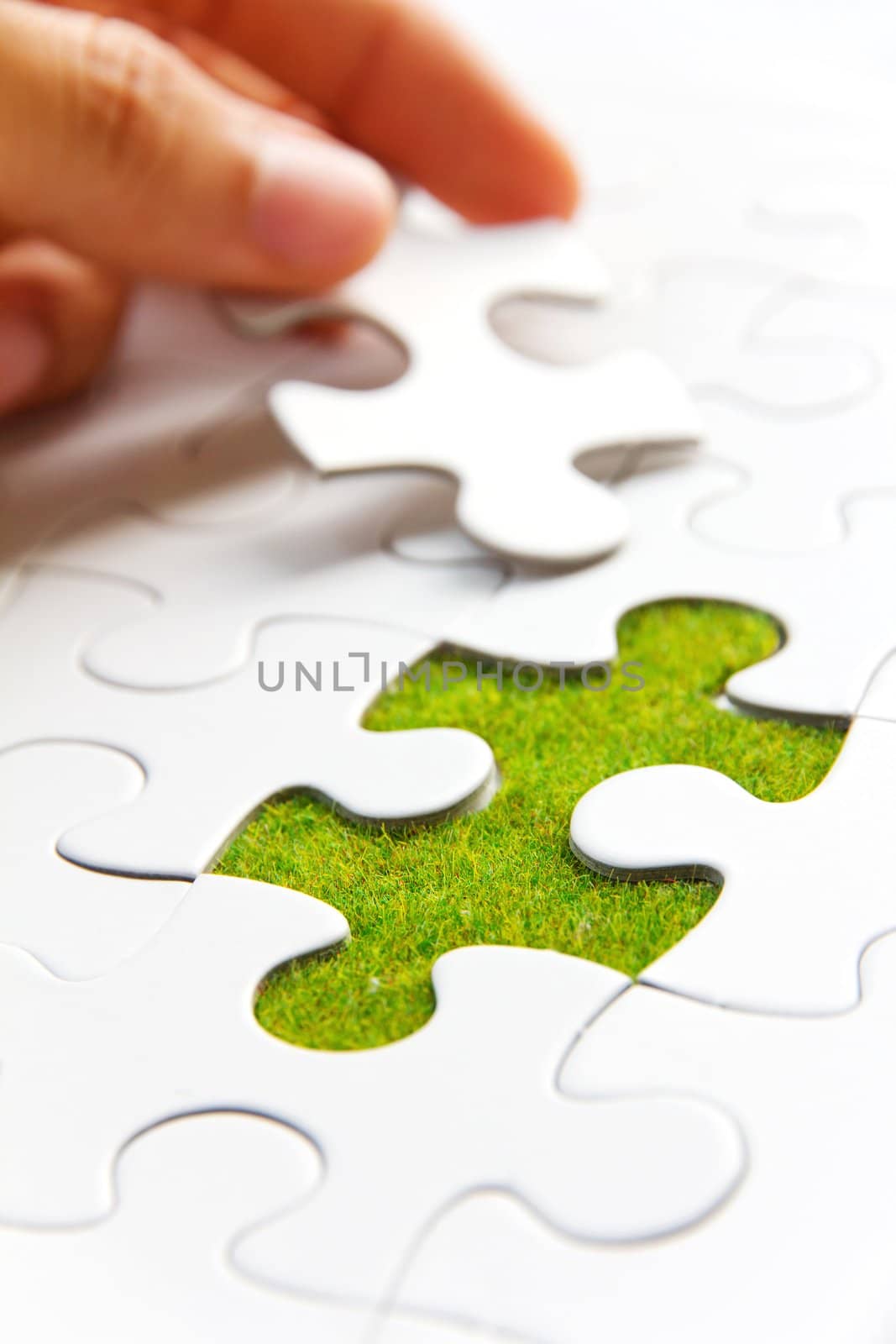 hand holding a puzzle piece, green space concept