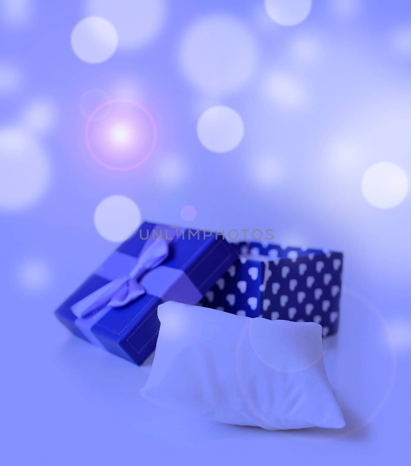 blue jewellery box with ribbon in bukeh background with little pillow to put your ring on