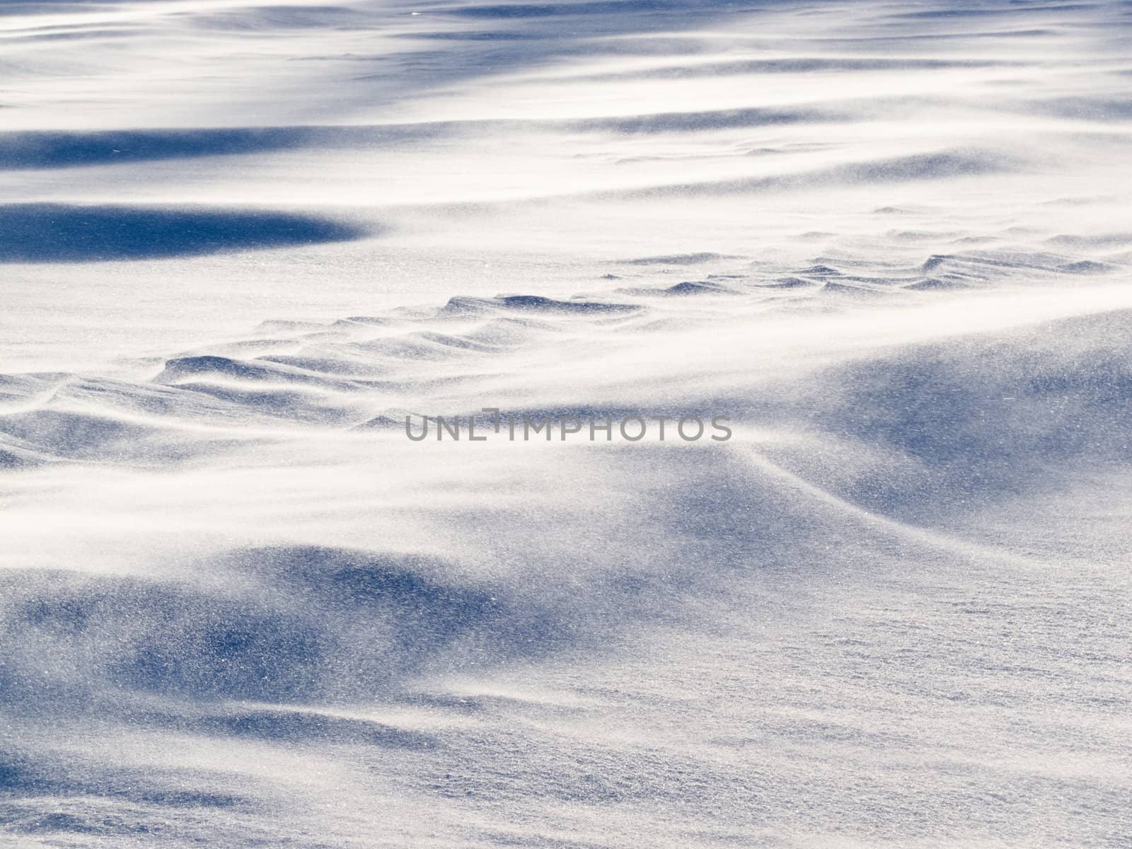 Blizzard background texture pattern: drifting snow crystals driven by strong wind creating snow surface refief