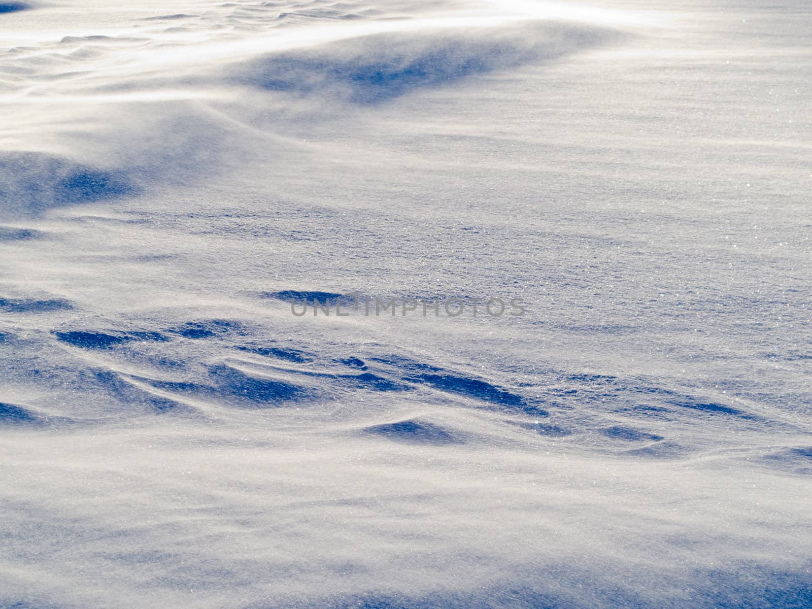 Blizzard background texture pattern: drifting snow crystals driven by strong wind creating snow surface refief