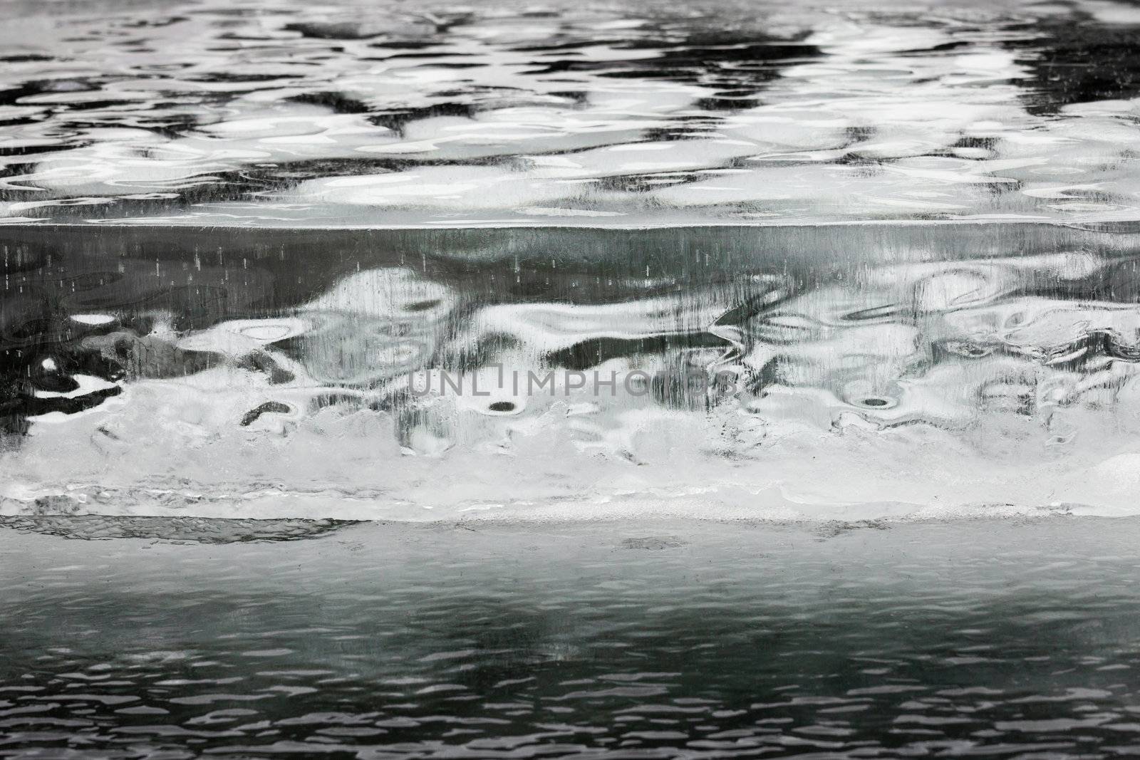 Thick layer of ice with straight crevasse crack and round trapped air bubbles background texture pattern