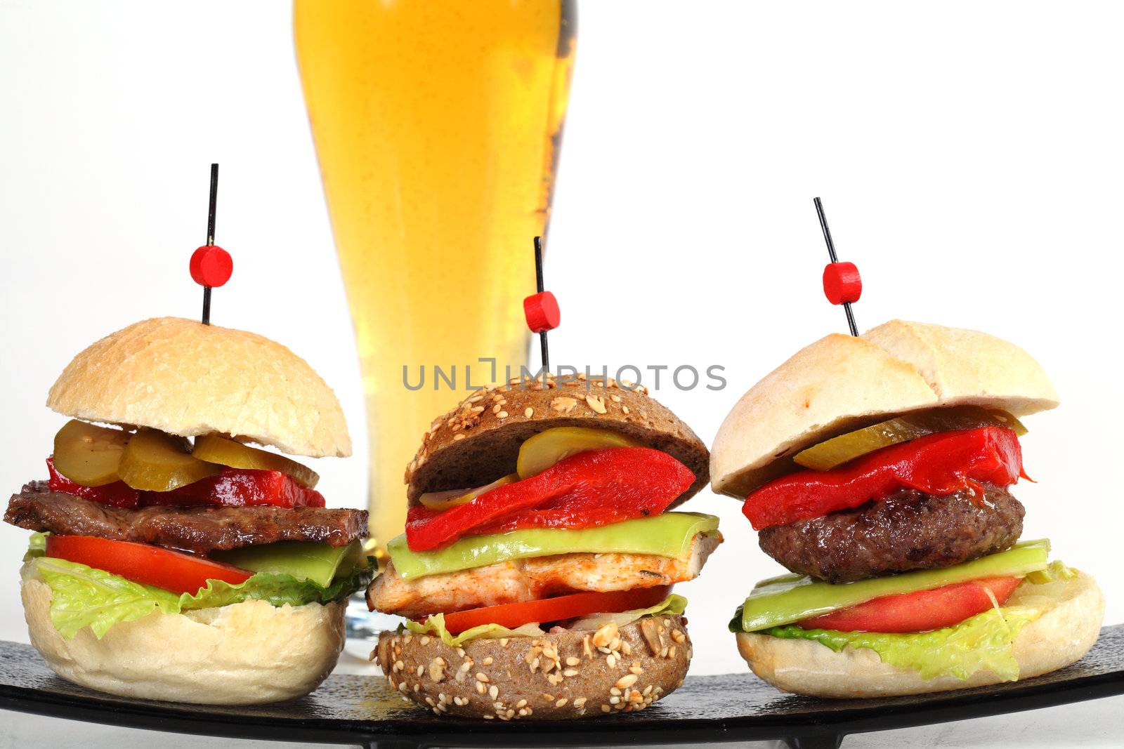 Three hamburgers on plate with glass of beer