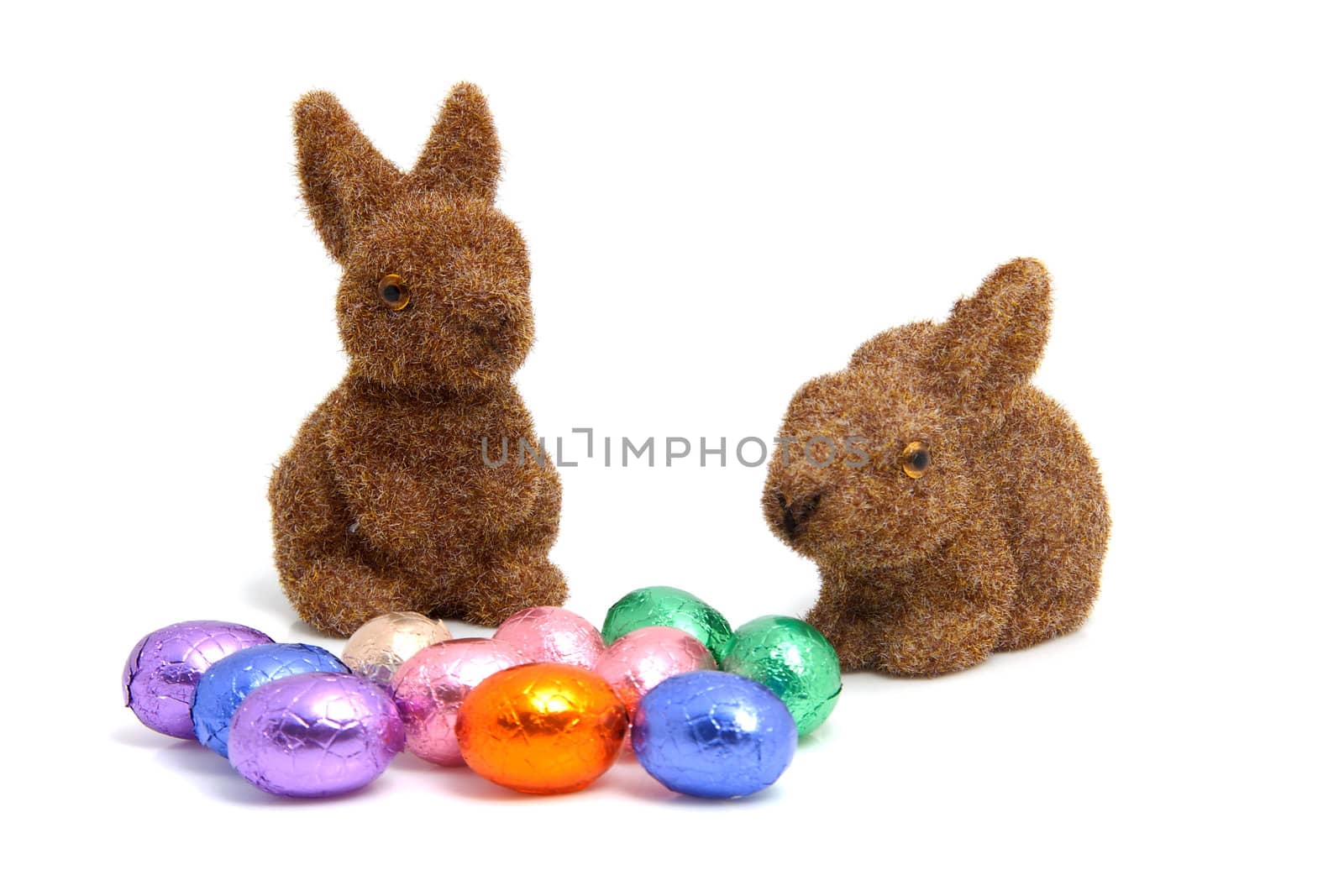 colorful chocolate easter eggs and brown bunnies over white background