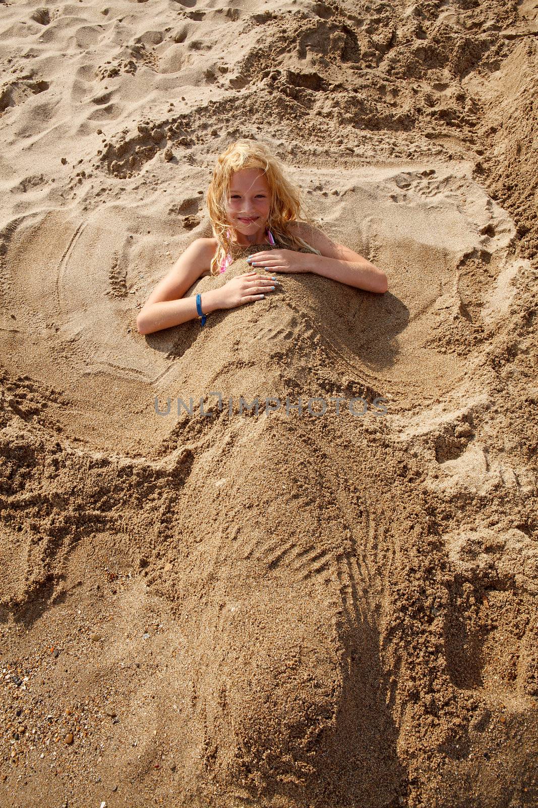 girl buried under sand is looking at you