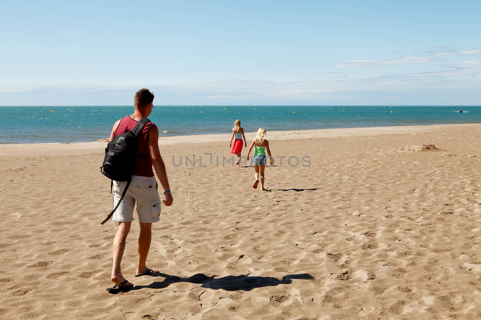 Family ( father and two daughters) walking on the beach 