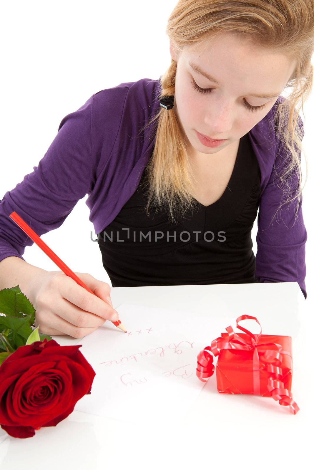 Young girl is writing Be my valentine in closeup with rose and present