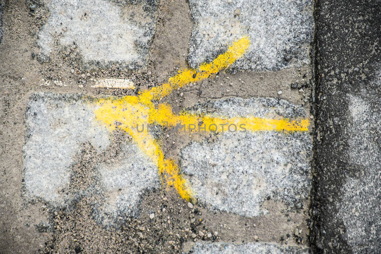 Yellow arrow on cobble stone pavement showing the right direction