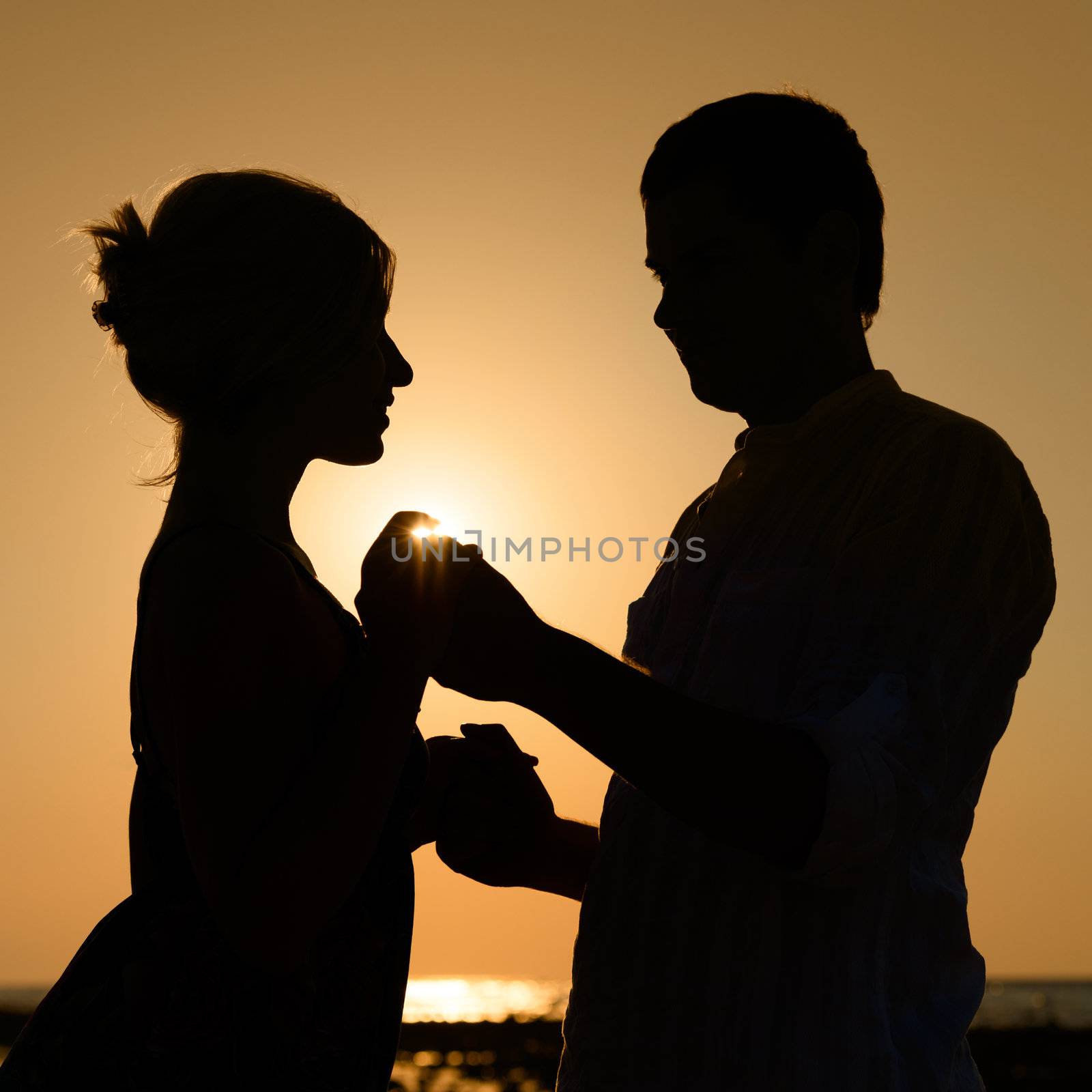 Silhouette of loving couple over orange sunset background 