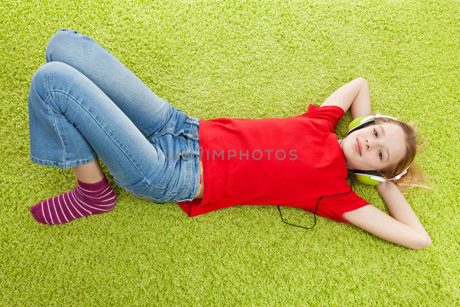 girl is listening to music with headphones on over green background
