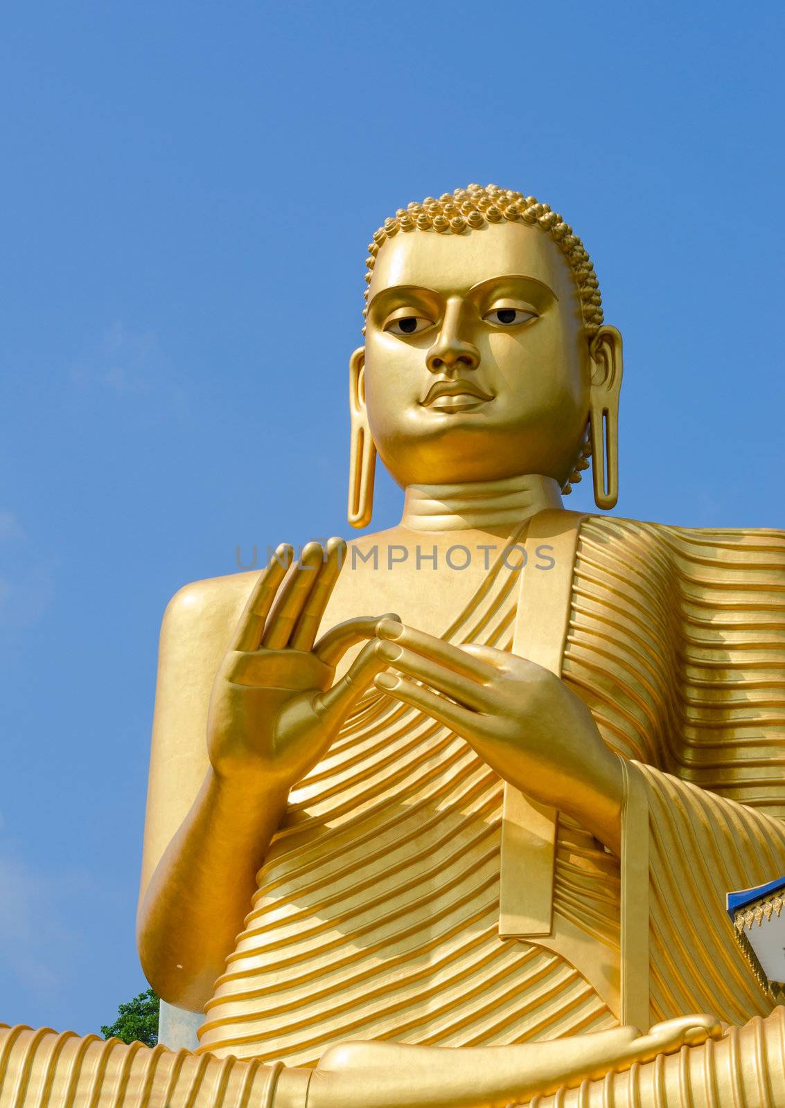 Golden yellow Buddha statue on blue sky background