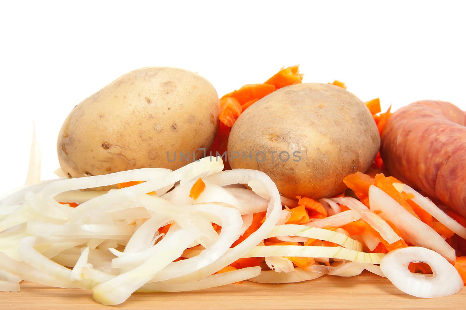 Ingredients for Dutch hutspot stew on wooden cutting board in closeup over white background