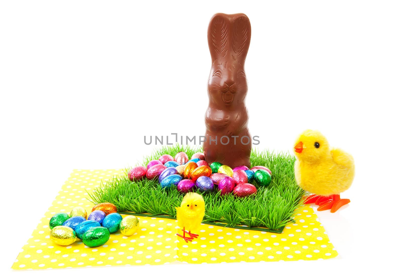 Easter scenery: chocolate  bunny and colorful eggs on napkin over white background