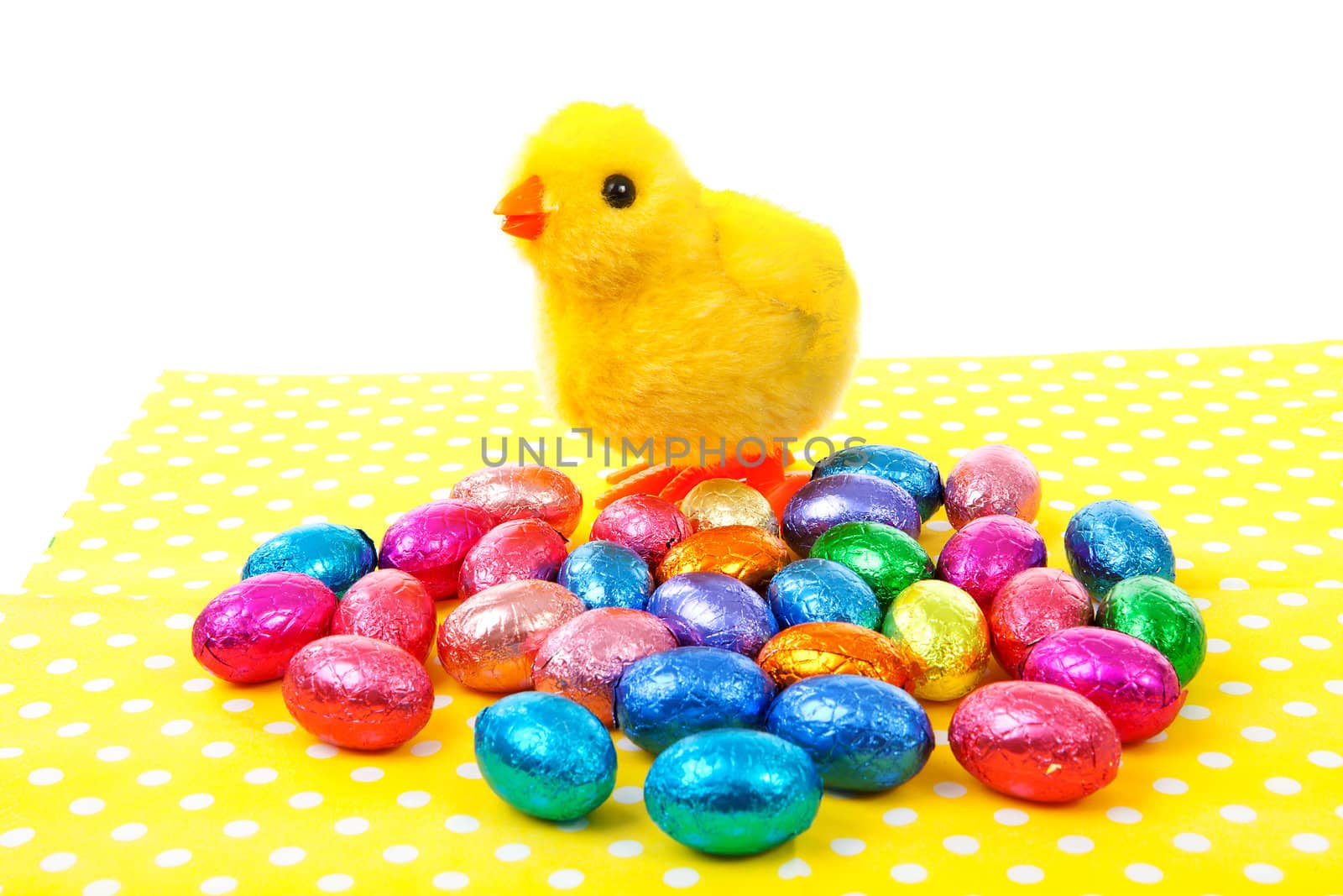 toy chicken and colorful easter eggs on napkin over white background
