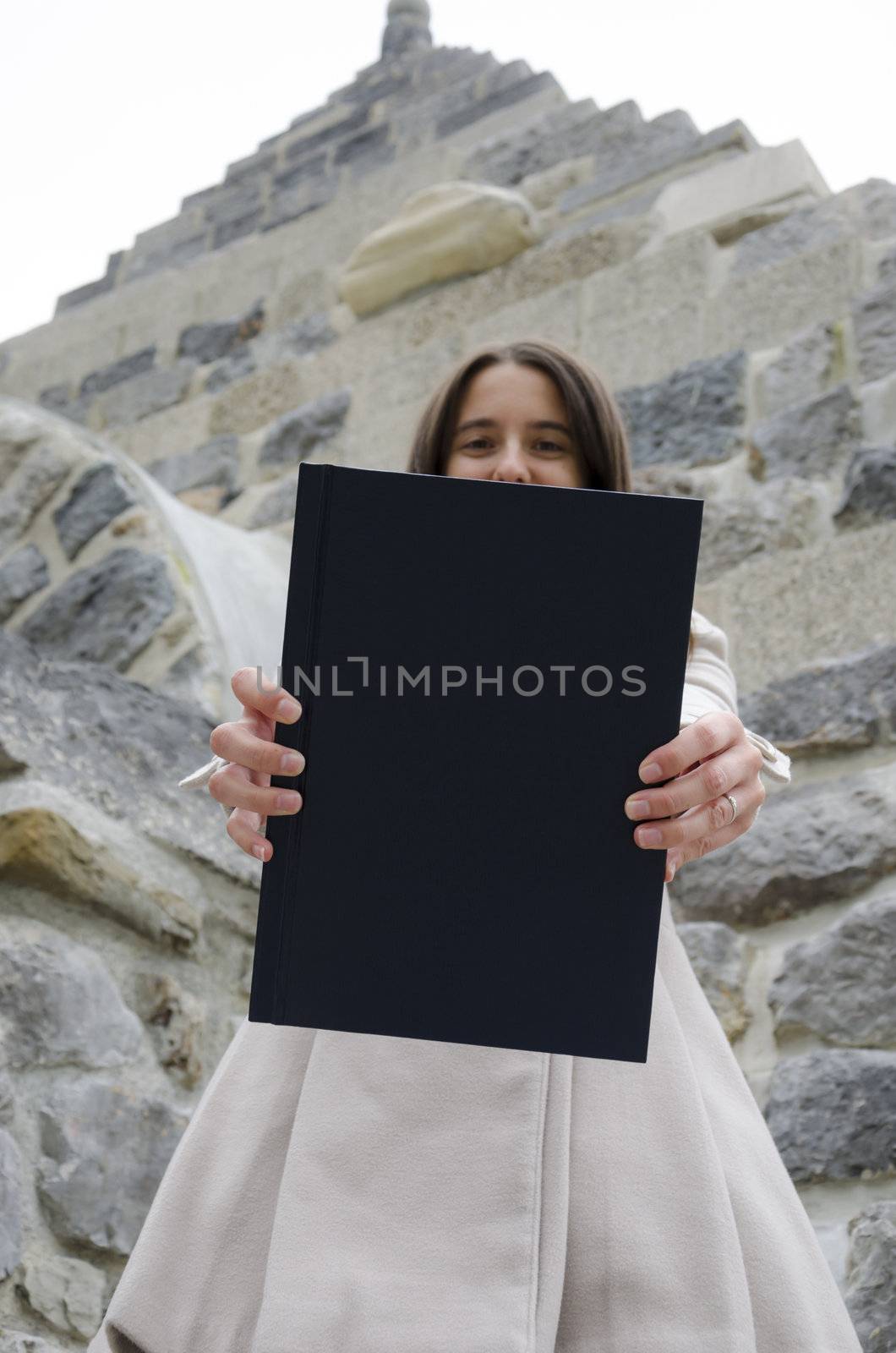 Girl holding degree dissertation. Empty space on book cover ready for text.