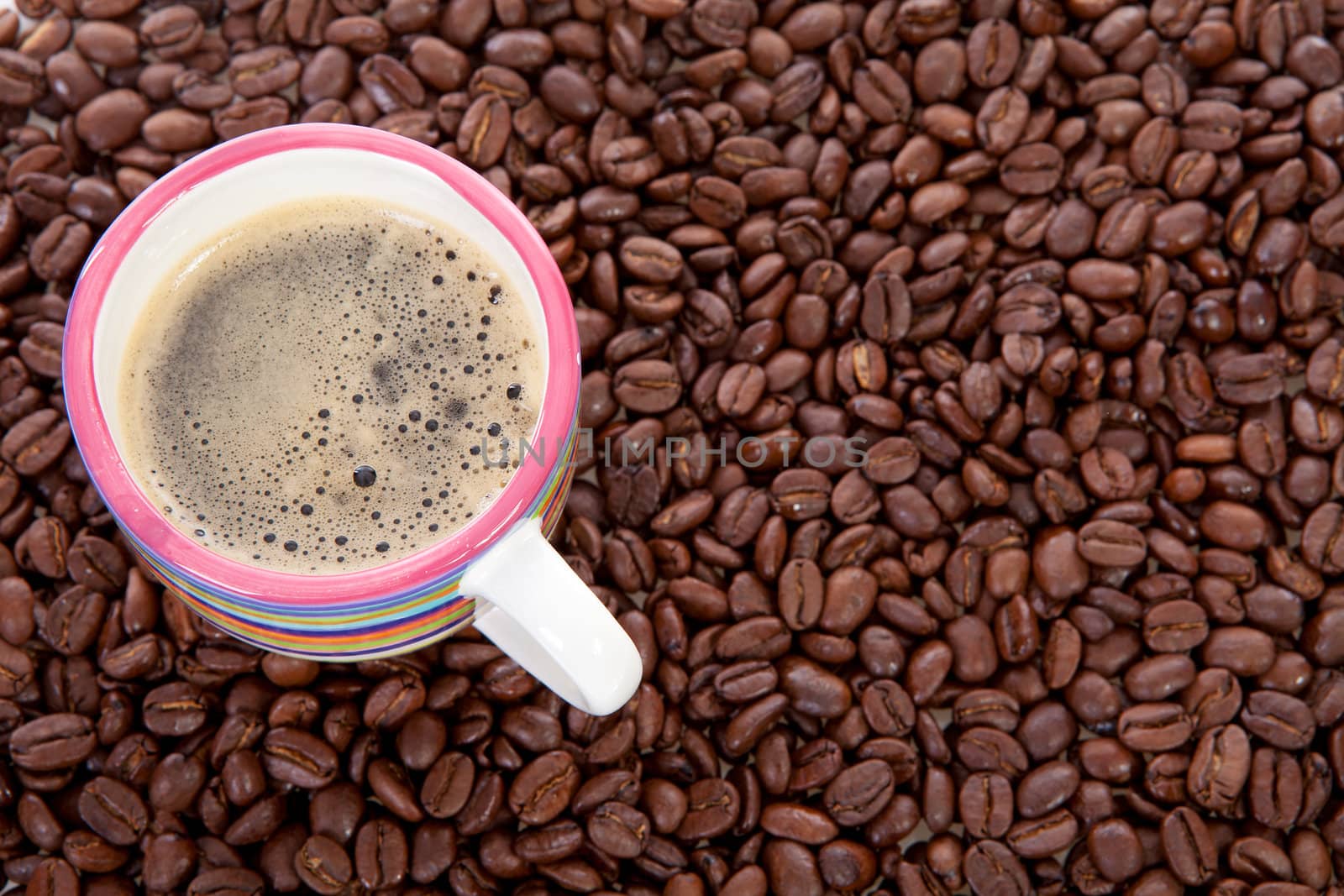Coffee cup in background of roasted beans