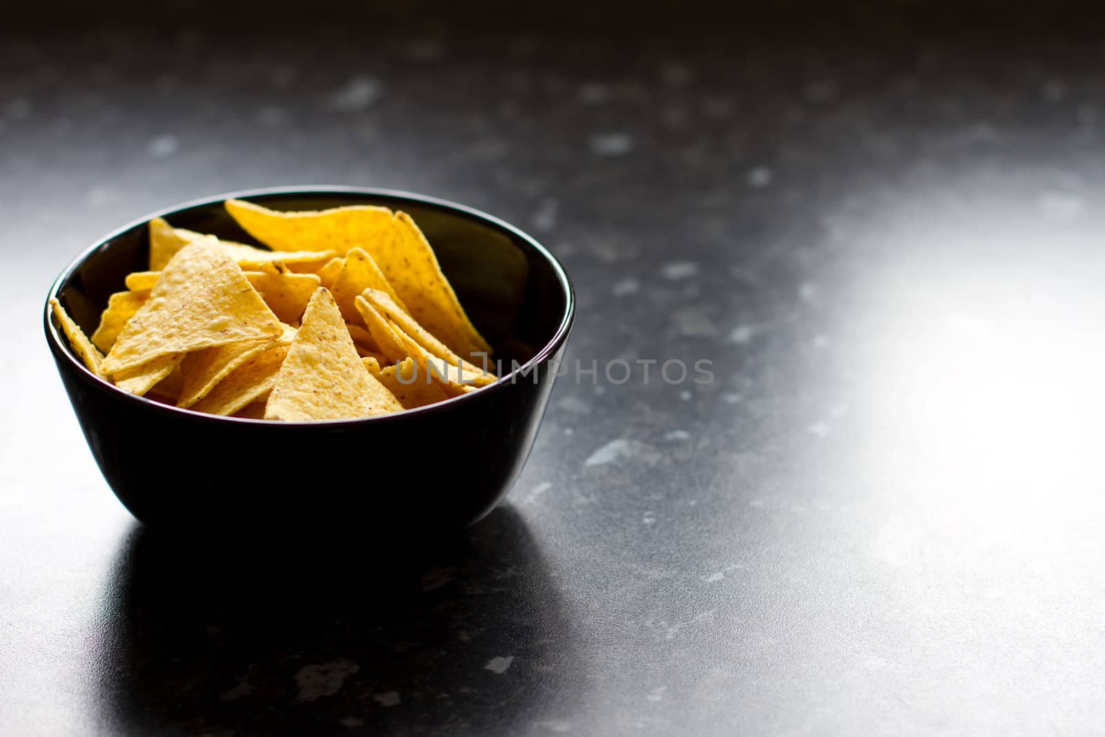 bowl of tortilla chips on a black kitchen counter