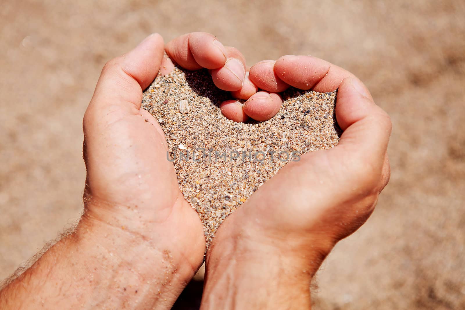 Hands in shape of hearts filled with sand