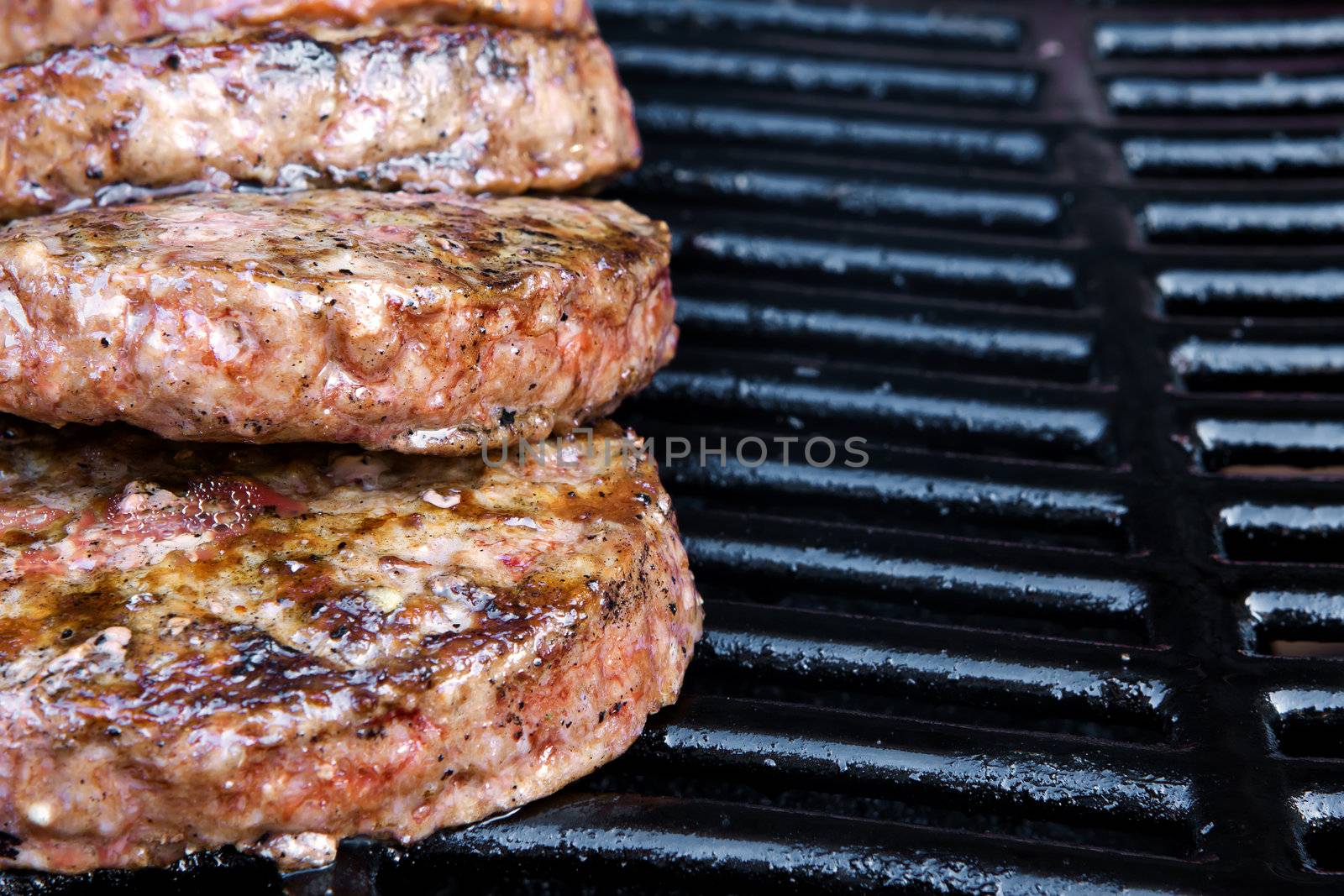 Beef quarterpounder burgers begin to cook on the gas barbecue