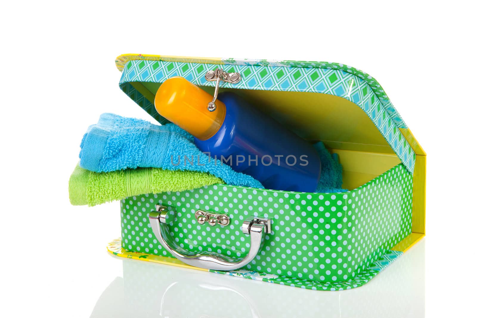 Suitcase, sunscreen and towels over white background
