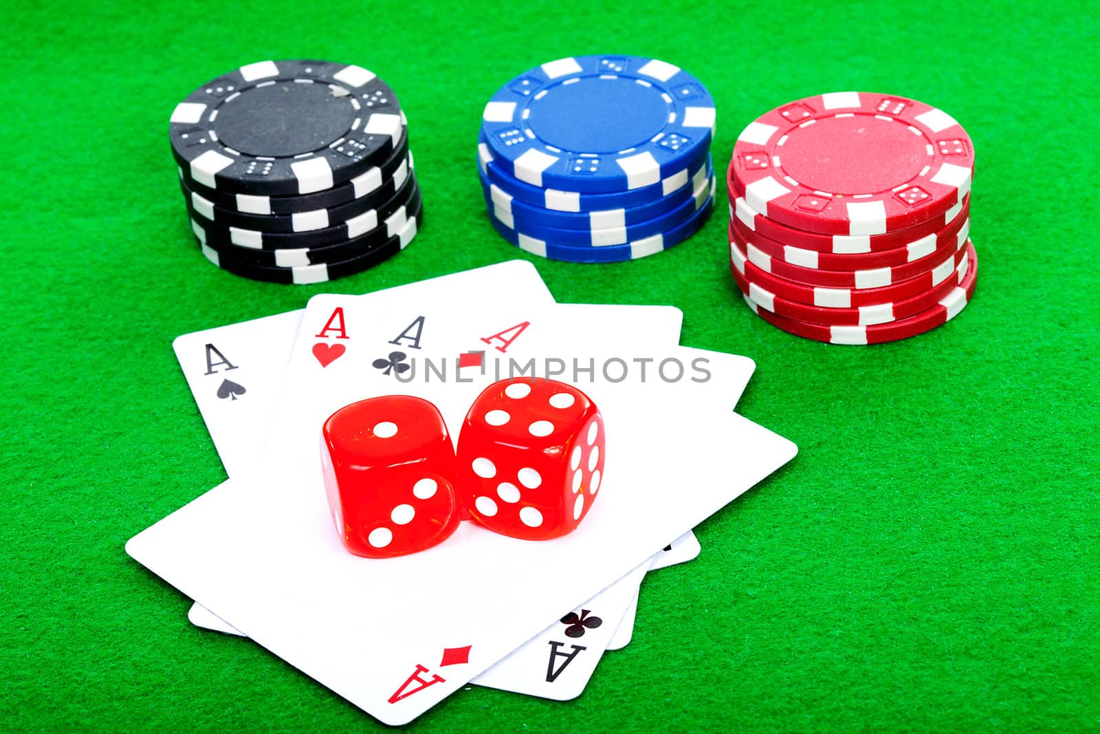 winning poker hand of four aces playing cards and red dice on green background