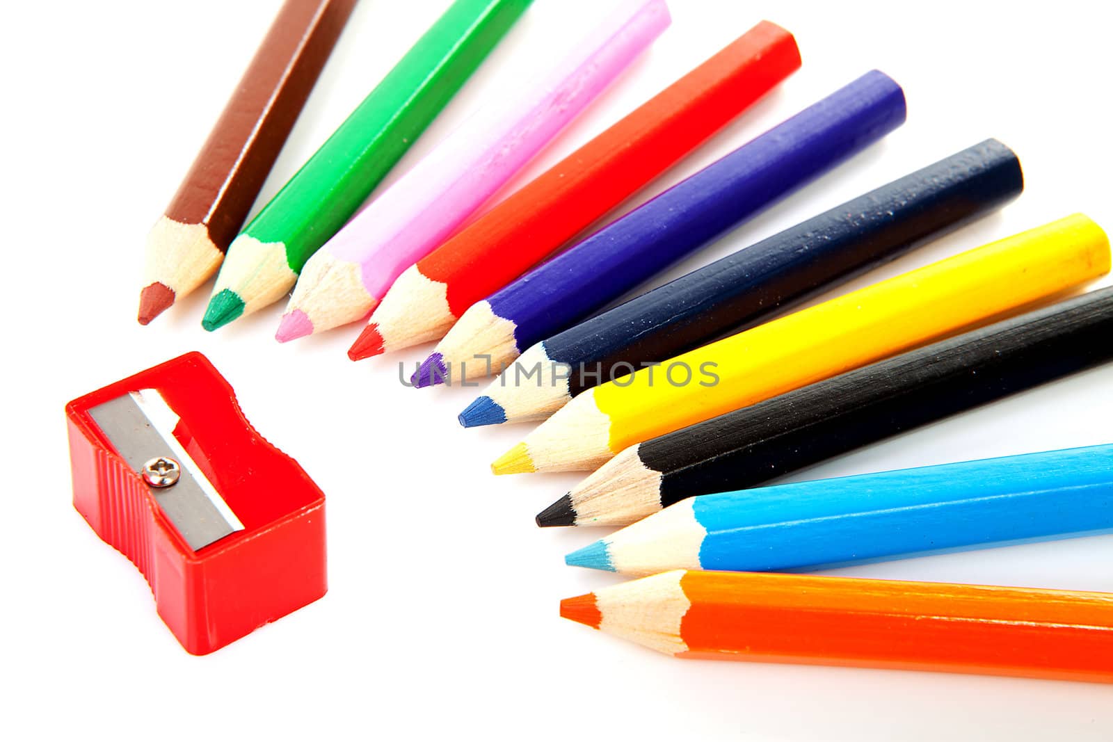 Colorful pencils and sharpener over white background