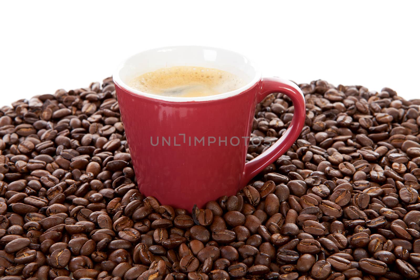 red coffee cup in pile of beans over white background