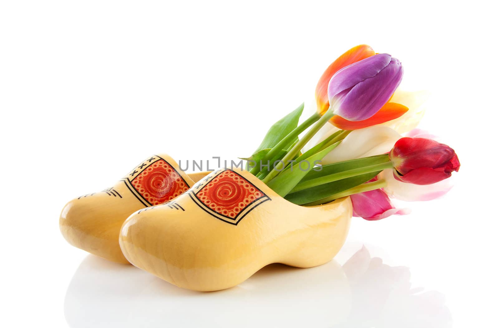 Pair of traditional yellow wooden shoes with colorful tulips isolated on white background