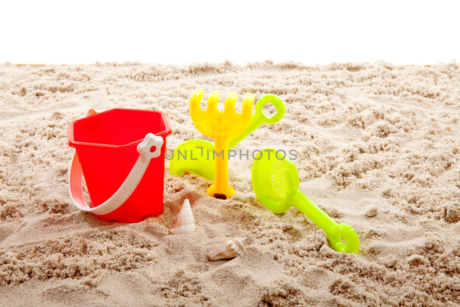 plastic play toys on sand over white background