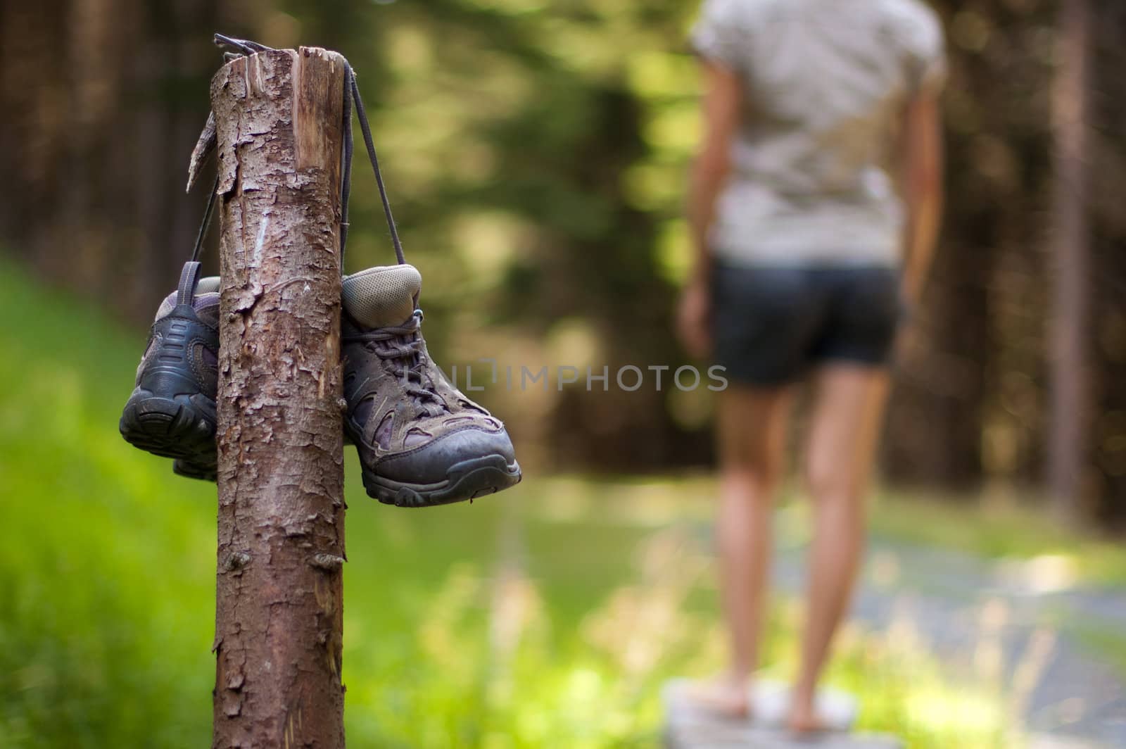 Abandoned hiking shoes with a woman walking bare feet