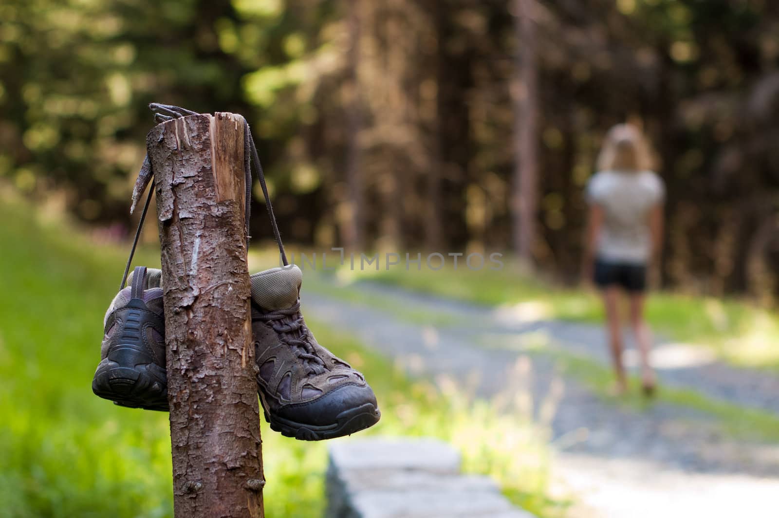 Abandoned hiking shoes with a woman walking bare feet