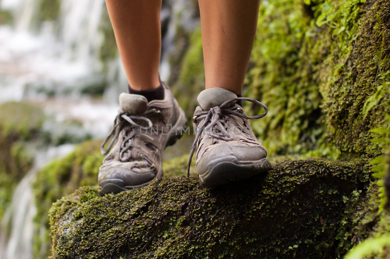 Closeup of a hiking boots with a waterfall in a background