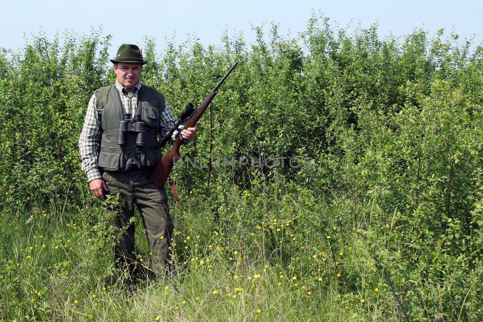 hunter with rifle standing in bush