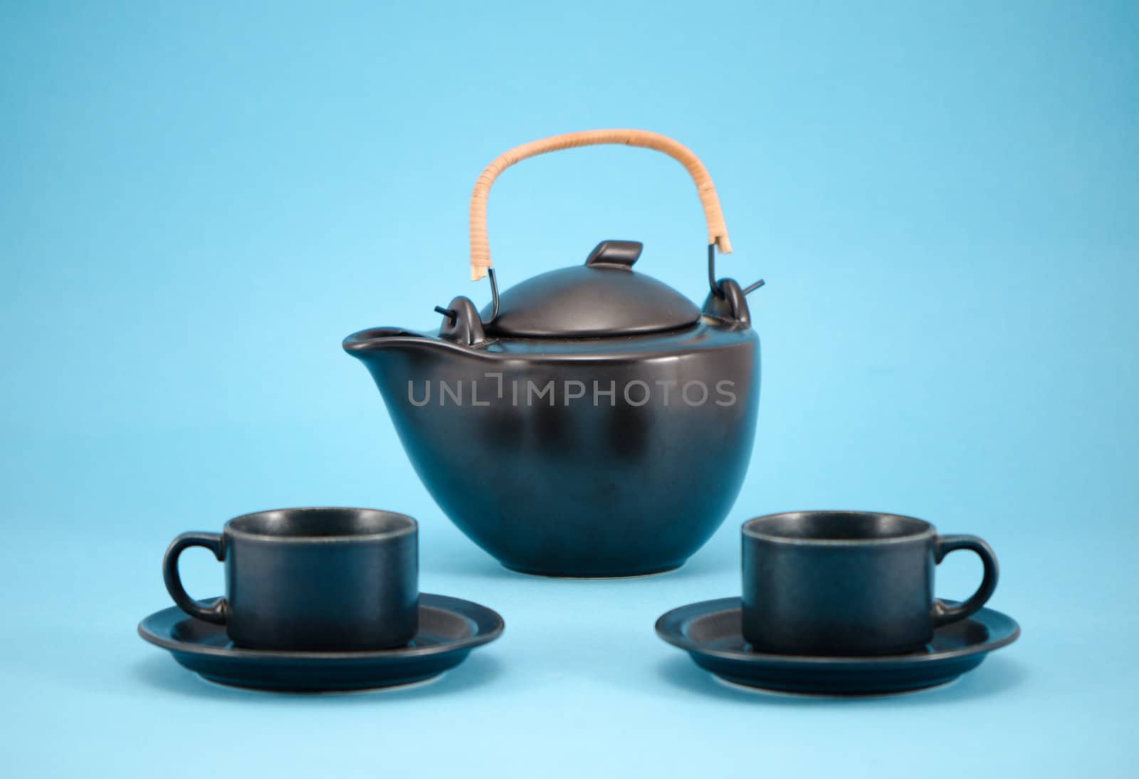 beautiful morning drink dish composition retro black teapot and small cups in saucers on blue background.