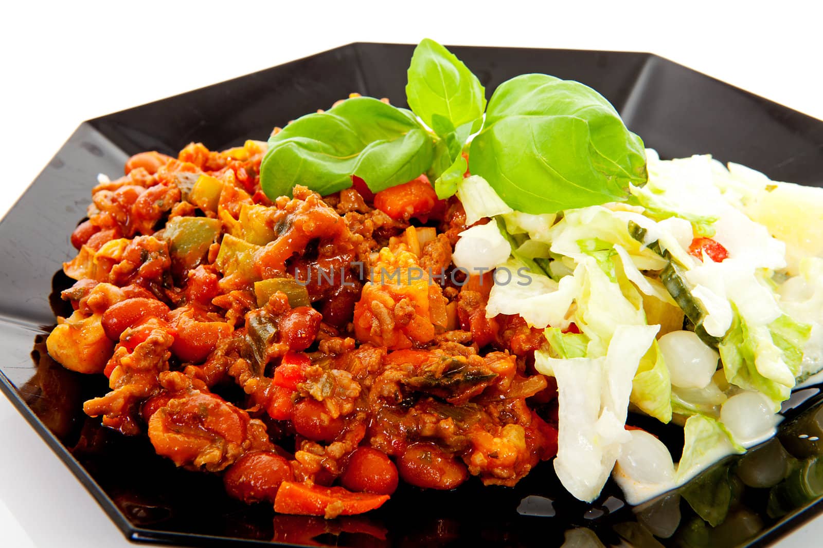 plate with delicious chilli con carne and salad over white background