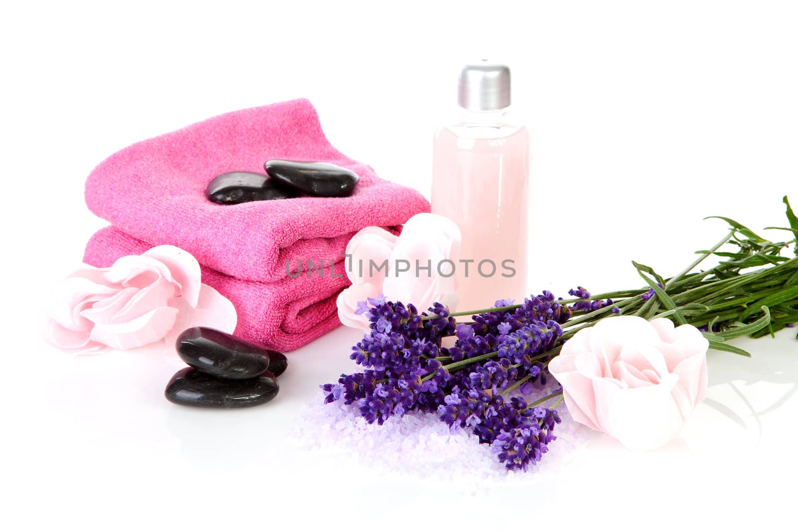 Spa accessories: stacked black pebbles stones, pink towels and lavender flowers over white background