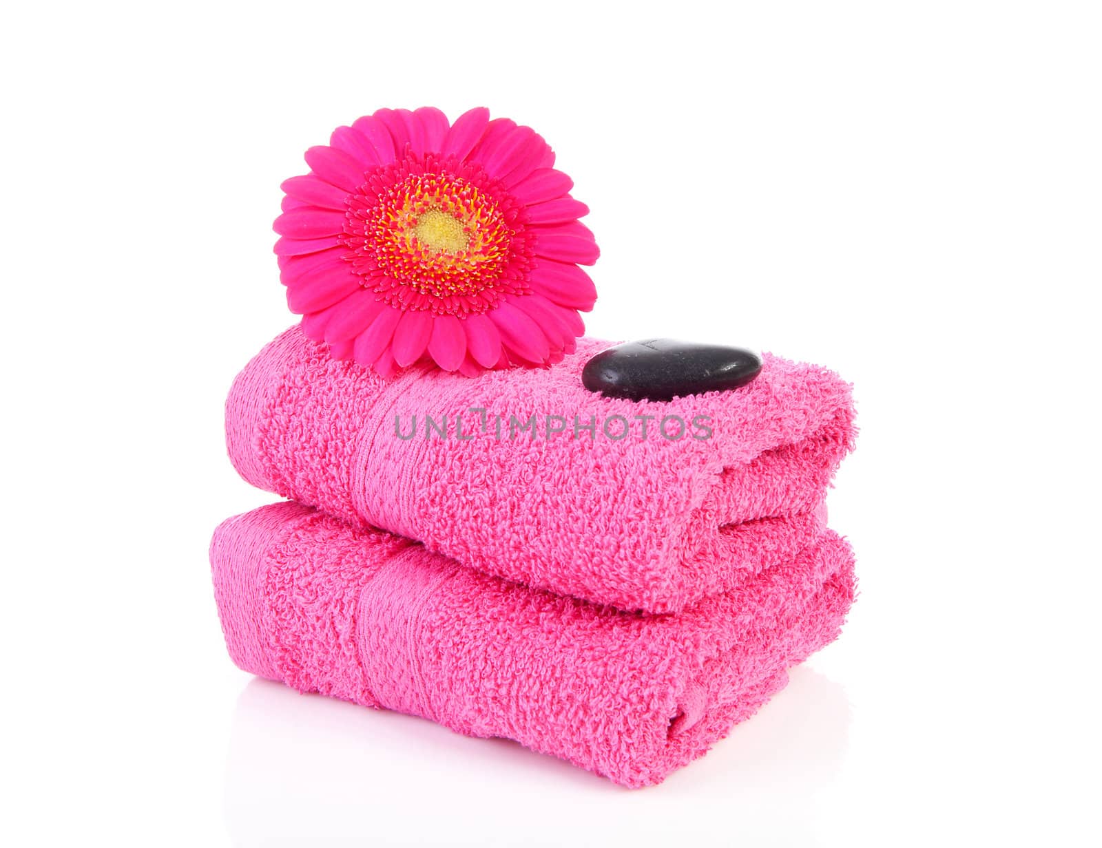 Pink bathroom accessories with towel, stones and Gerber flower over white background