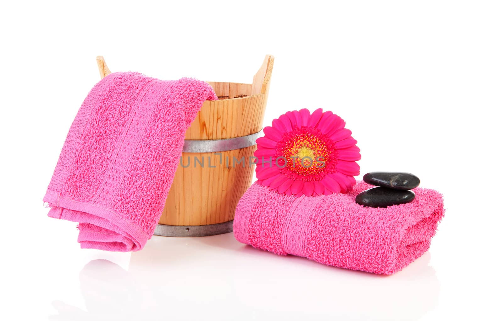 Pink bathroom accessories with towel, stones and Gerber flower over white background
