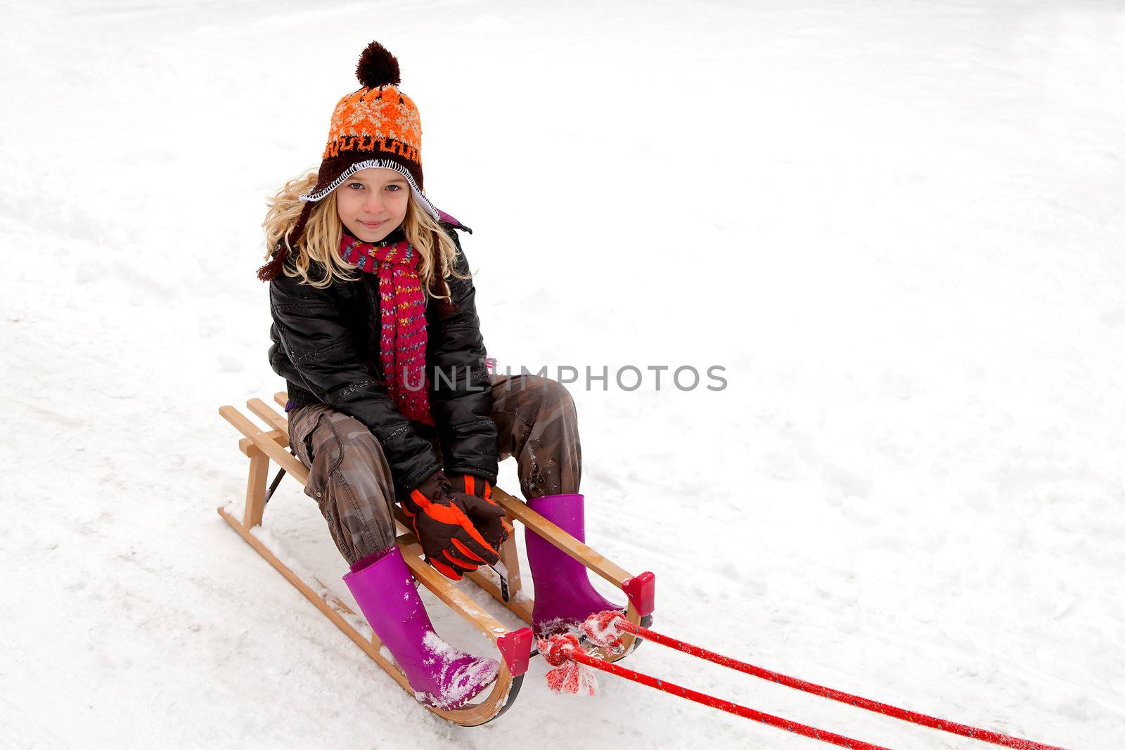 Girl on sled in the snow looking into camera