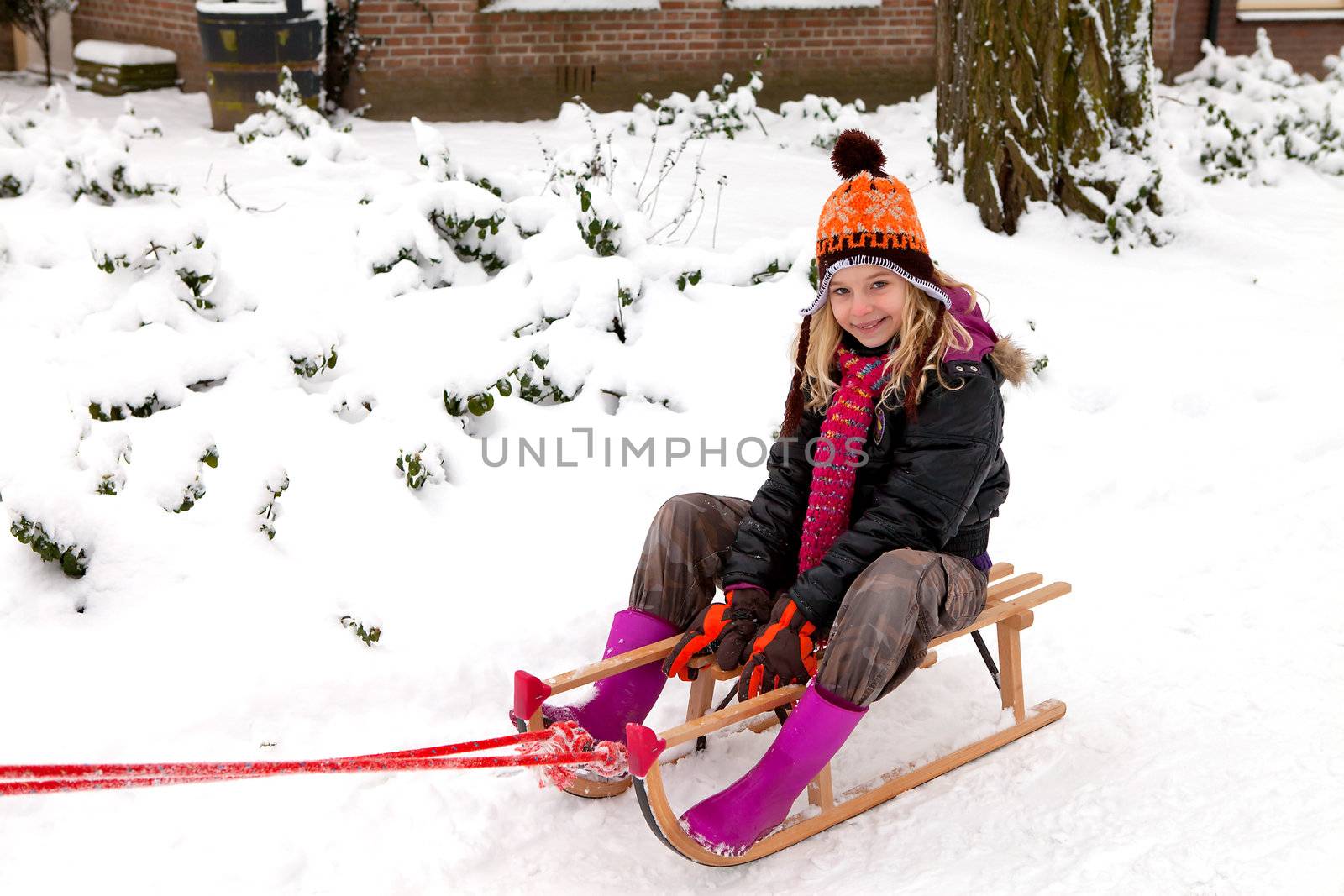 Girl on sled in the snow looking into camera