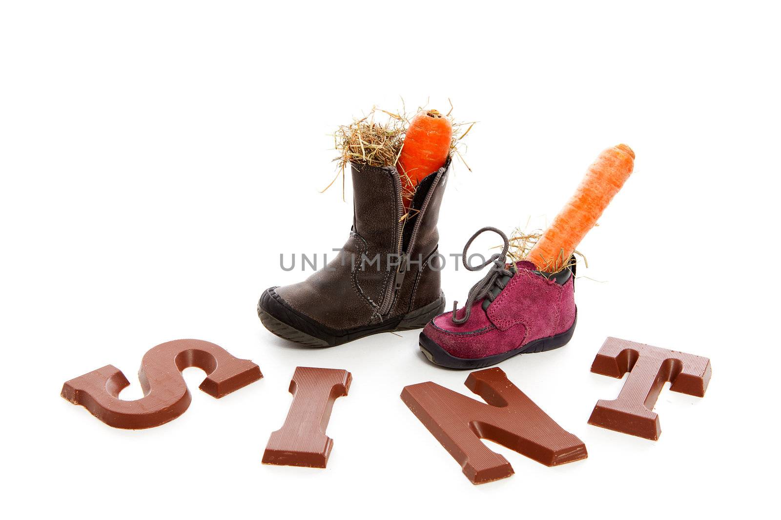 Sinterklaas, typical Dutch event with chocolate letters and carrot in shoes over white background