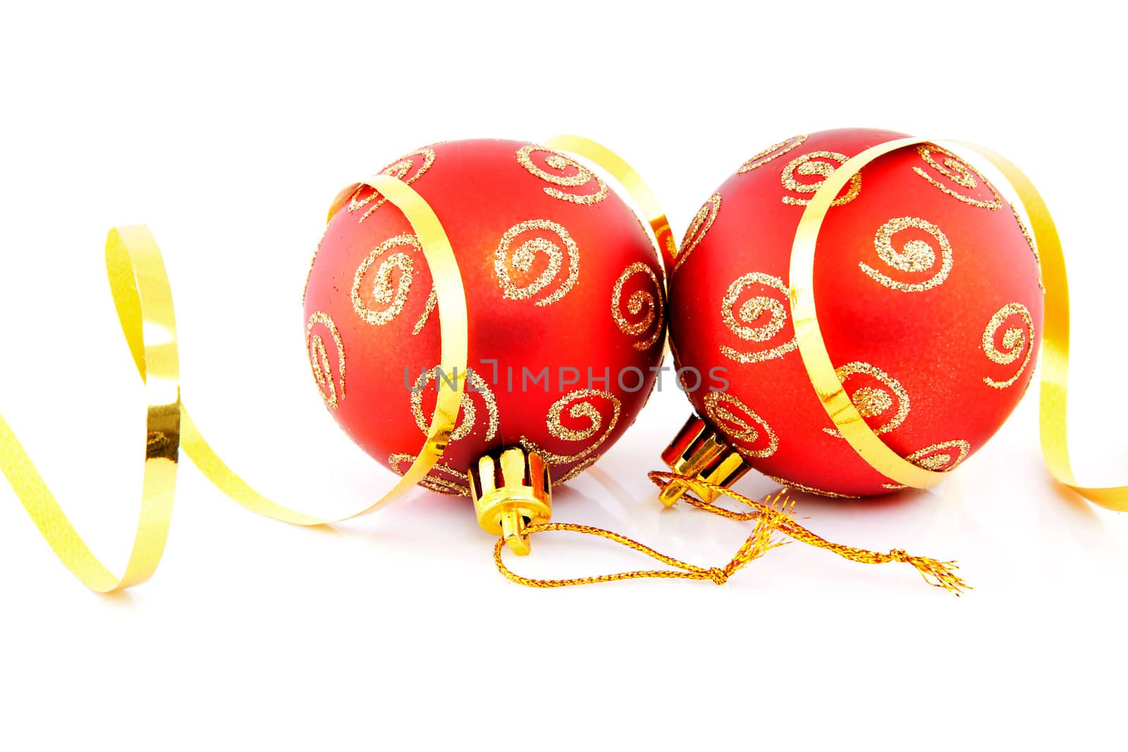 Two red christmas balls and golden ribbon over white background