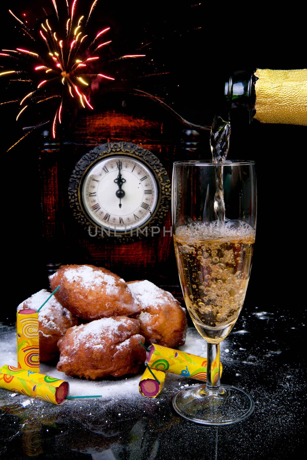 Dutch donut also known as oliebollen, traditional New Year's eve food and clock on midnight, firework, champagne over black background
