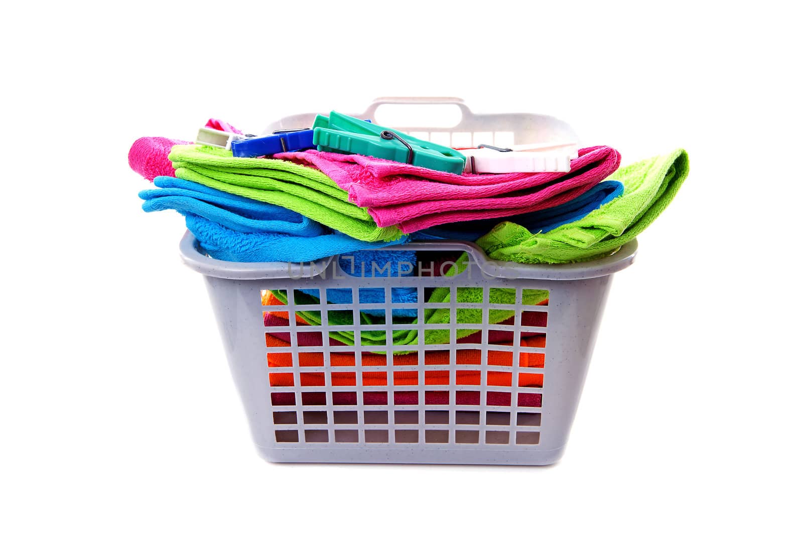 Laundry basket filled with colorful towels and pegs over white background