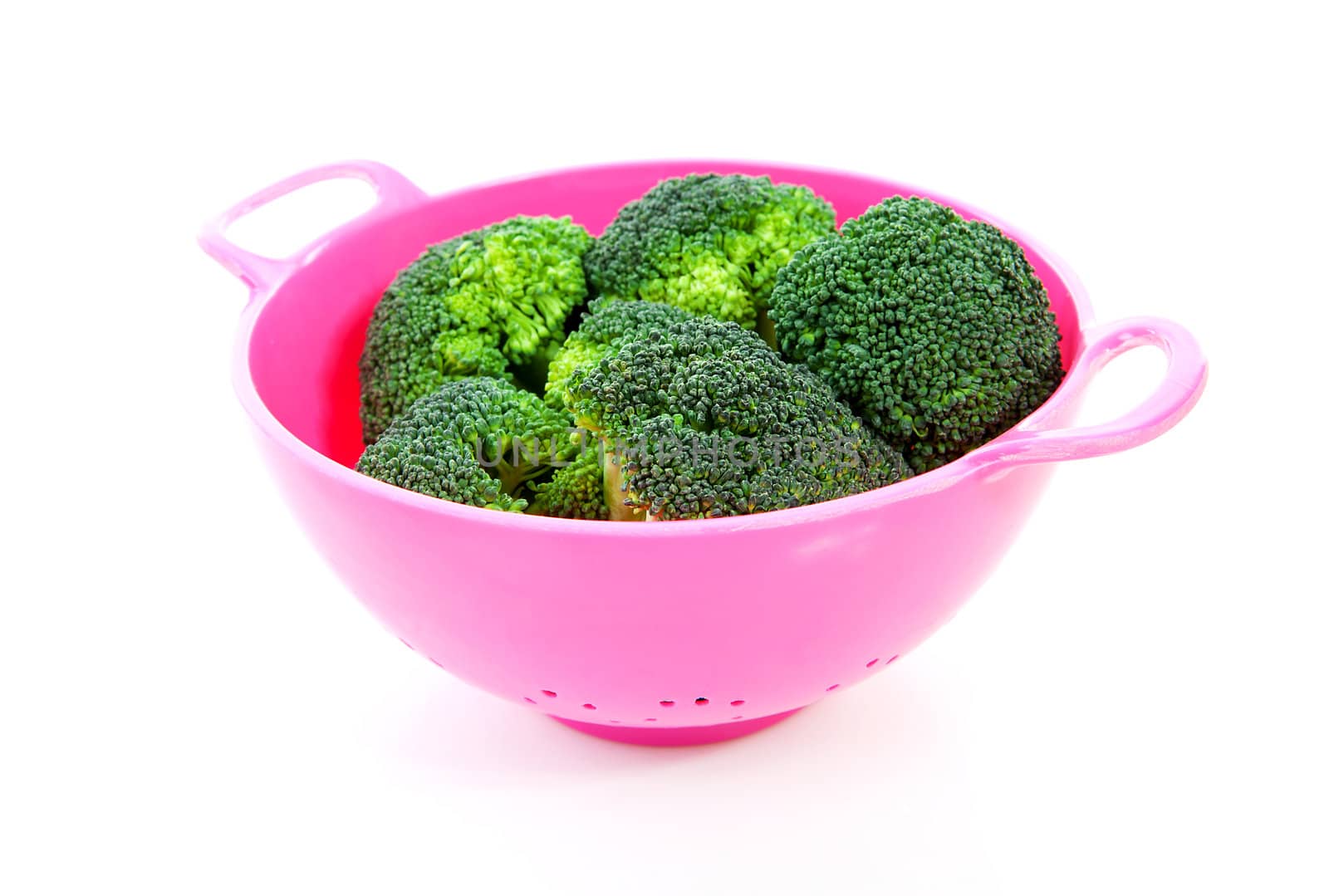 pink colander with broccoli vegetable over white background