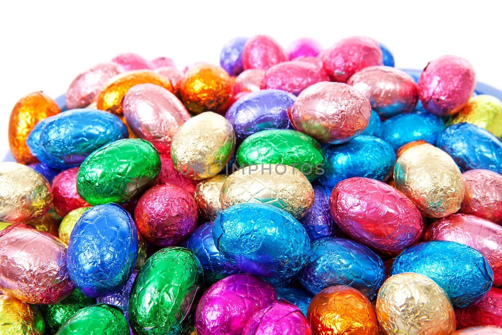 Pile of colorful easter eggs in closeup over white background