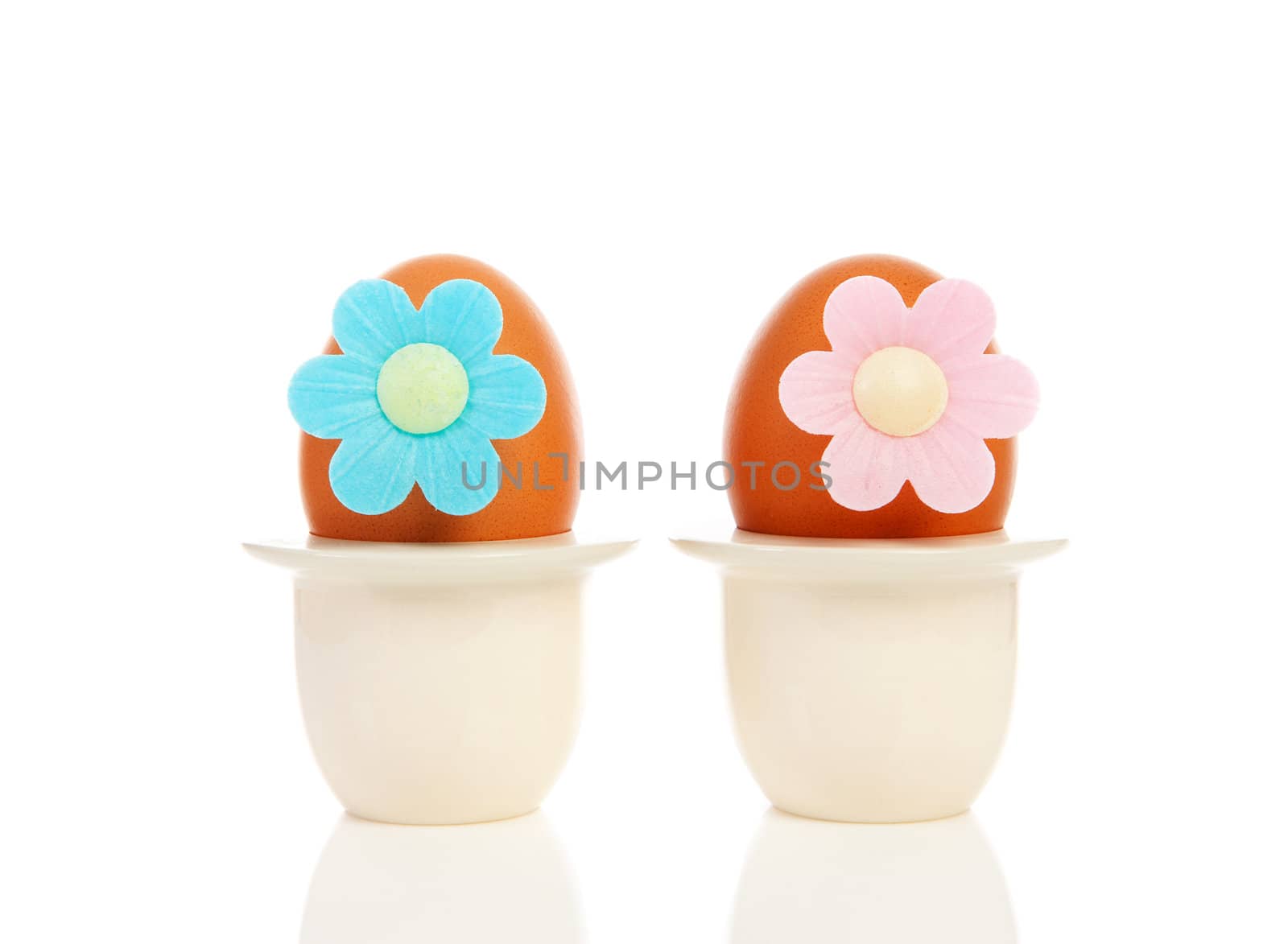 Two chicken eggs in holder with flowers over white background