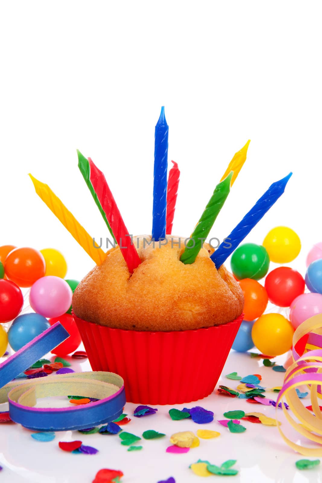 Birthday cupcake with lots of candles, party streamers and colorful confetti over white background