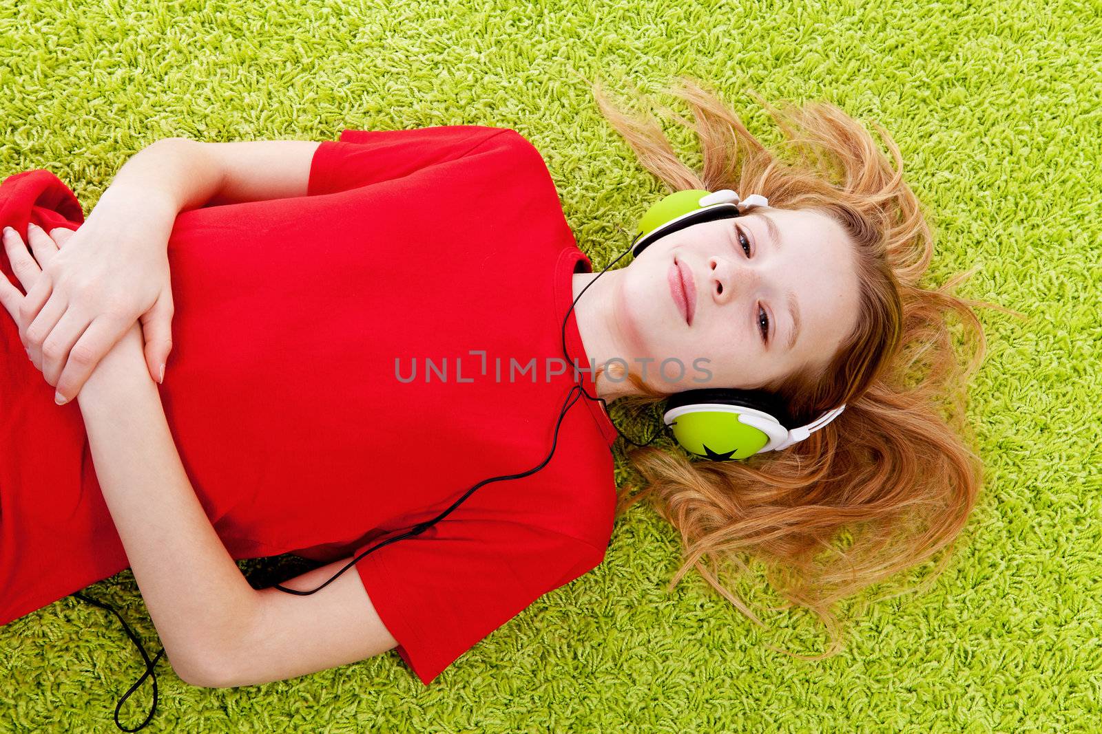 girl is listening to music with headphones on green carpet
