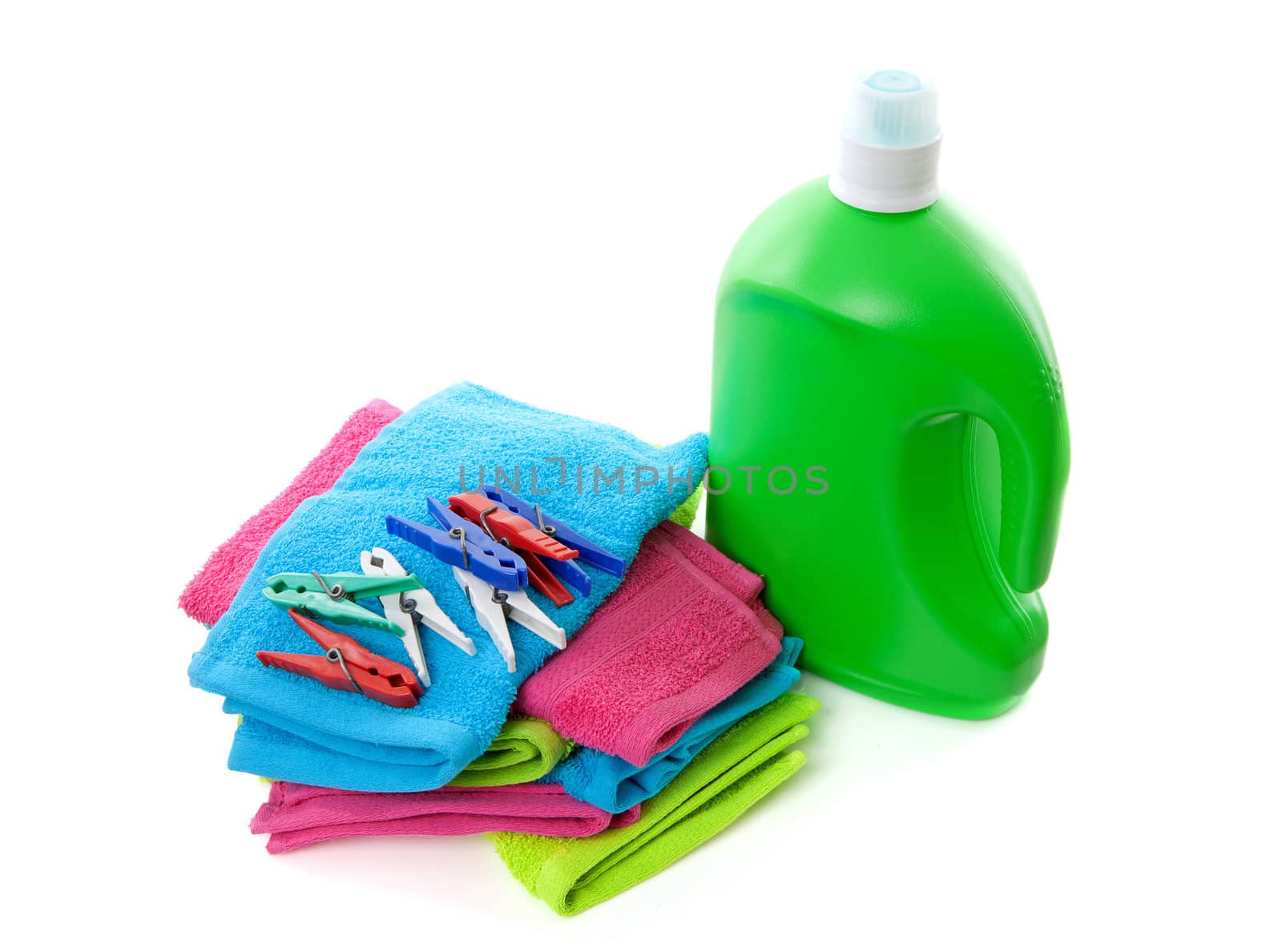 colorful folded towels, pegs and bottle over white background