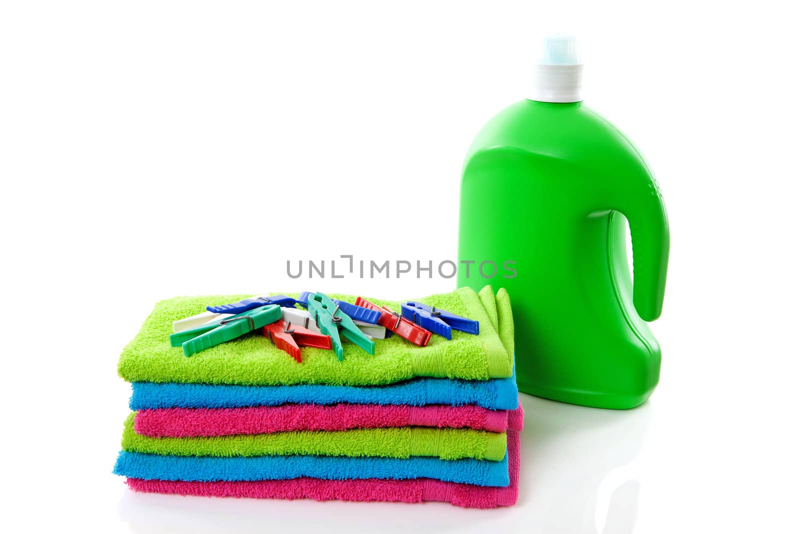 colorful folded towels, pegs and bottle over white background